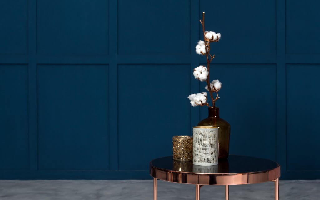 Modern Vases on metal copper side table in room with blue wooden walls
